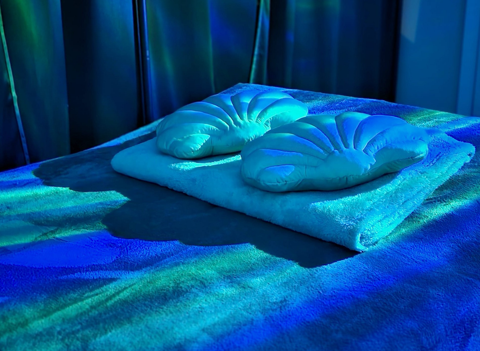 Massagetafel met gevouwen handdoeken in zacht blauw licht