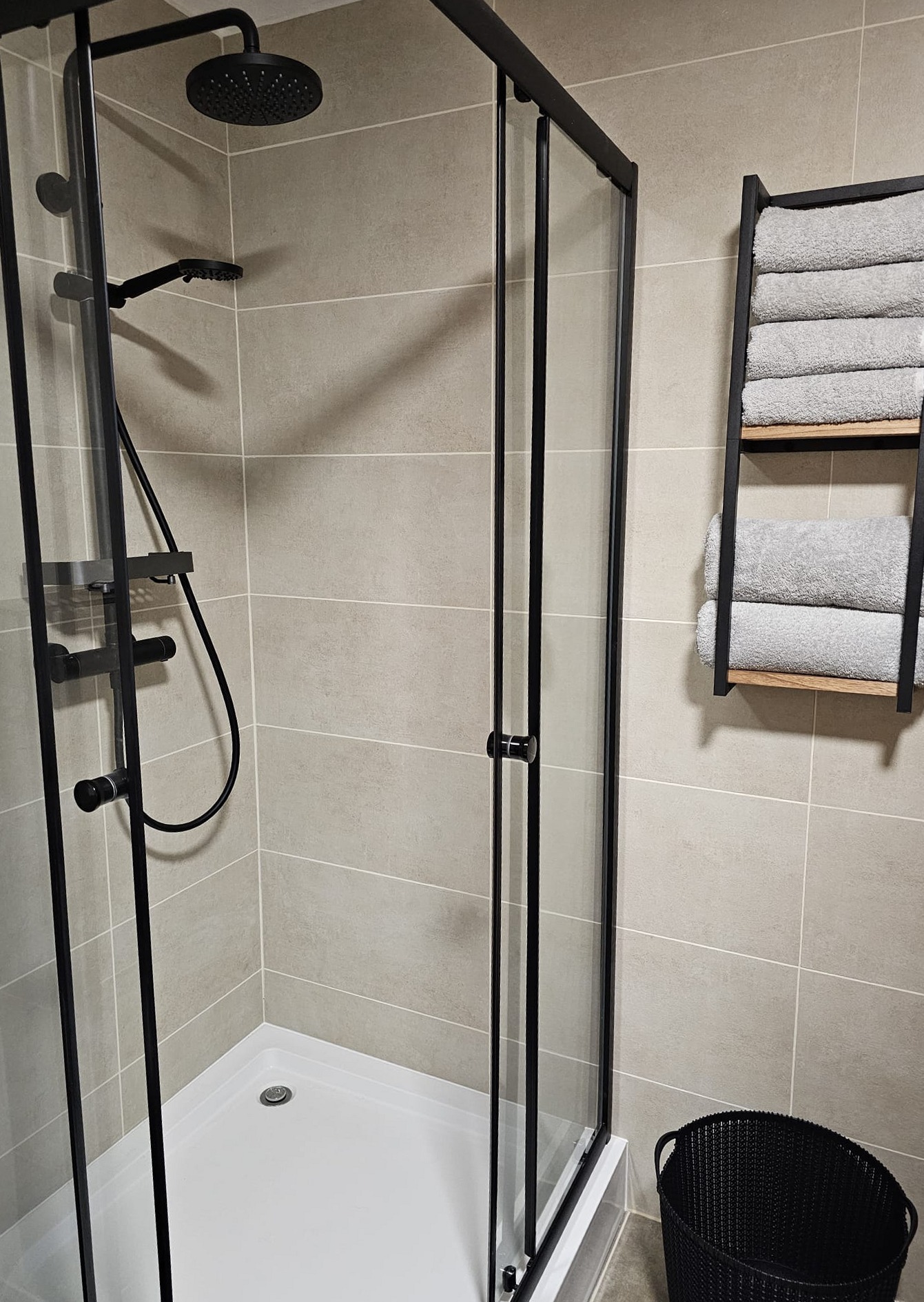 Douche met glazen wand en een rek met handdoeken